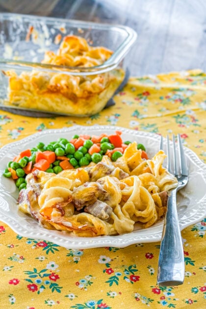 Cheesy roast beef casserole served with peas and carrots.