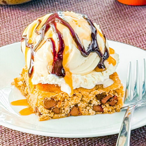 Close-up of gooey Chocolate Chip Paradise Pie with vanilla ice cream, caramel sauce, and chocolate sauce