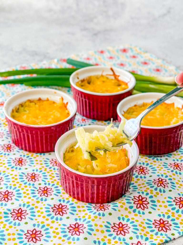 close-up of creamy shredded potatoes au gratin with melted cheese in ramekin