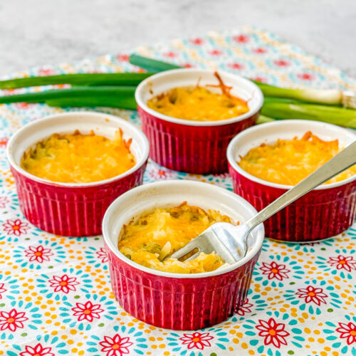 fork in creamy shredded potatoes au gratin with melted cheese in ramekin
