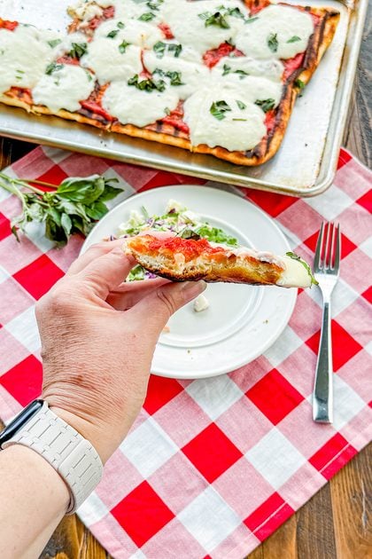 Crispy grilled pizza crust with melted mozzarella and basil leaves