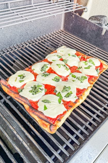 Margherita pizza cooking on the grill with a crisp golden crust
