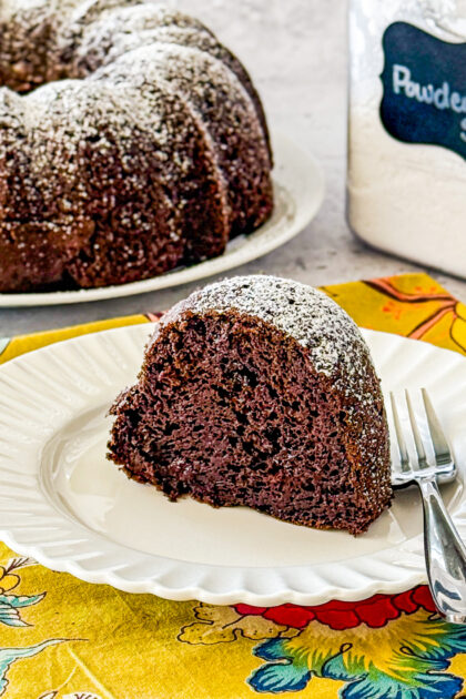 slice of rich chocolate bundt cake showing moist crumb dusted with powdered sugar
