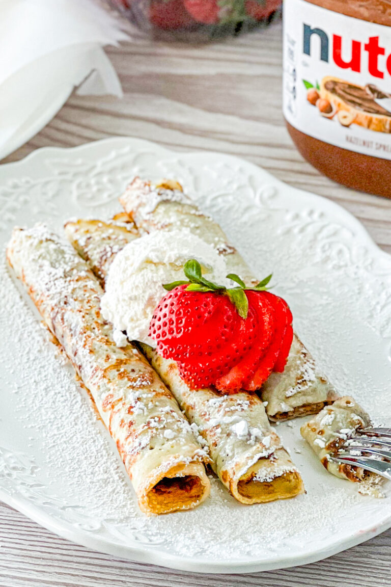 3 nutella crepes on a white plate srinkled with powdered sugar