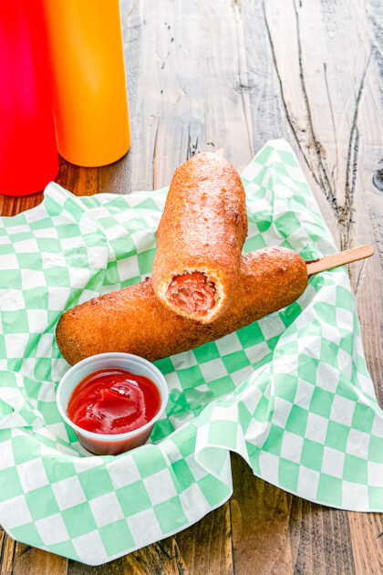 Homemade corn dogs served on a basket with dipping sauce