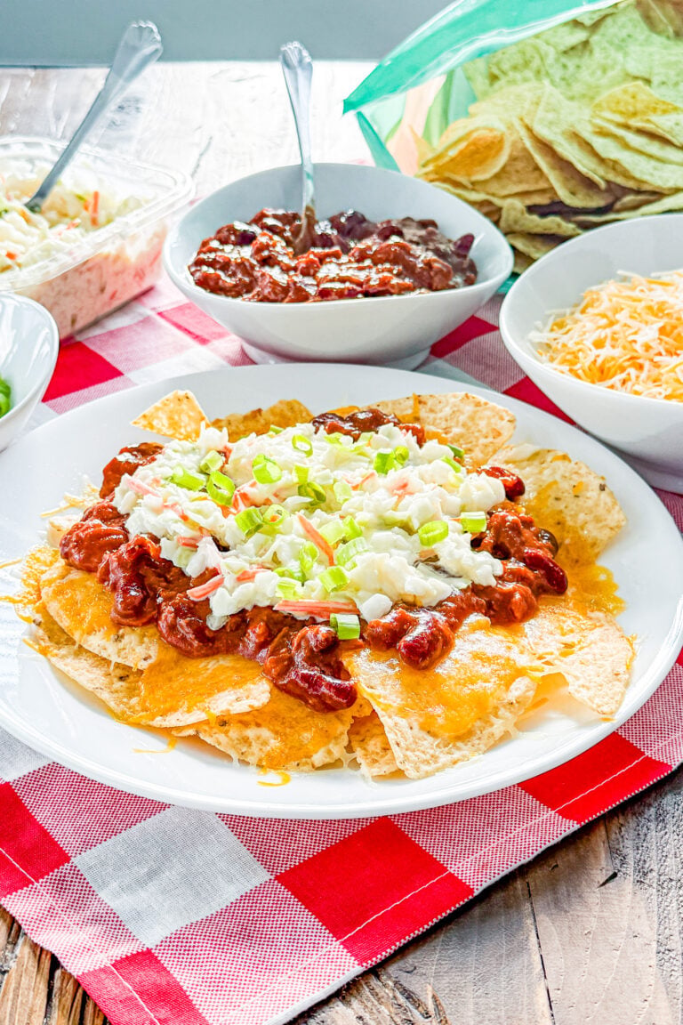 BBQ pulled pork nachos topped with cheddar cheese, chili beans, coleslaw, and green onions