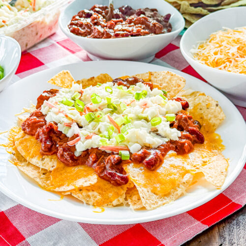 Cheesy pulled pork nachos topped with creamy coleslaw and green onion