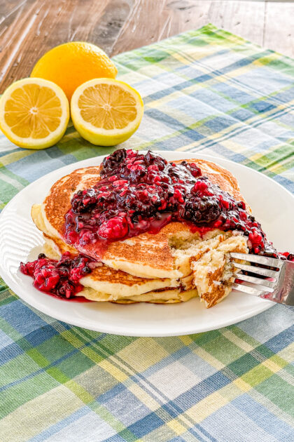 Lemon ricotta pancakes topped with warm blackberry sauce on a plate