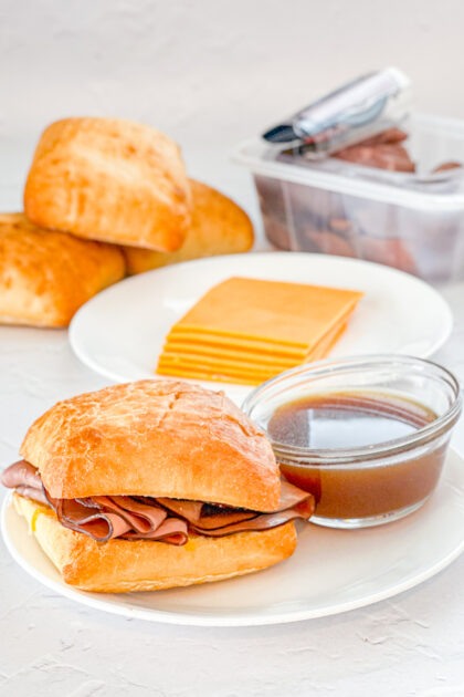 Cheddar Cheese French Dip SAndwich on a plate next to small bowl of au jus