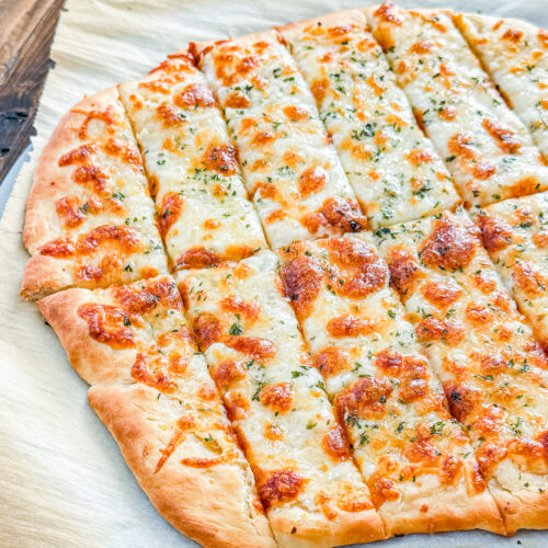 Close-up of cheesy garlic breadsticks with browned mozzarella