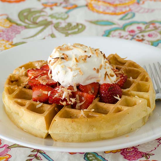 Close view of a Belgian waffle topped with coconut syrup and Cool Whip