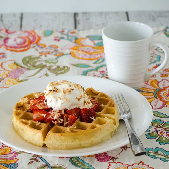 Belgian waffles with coconut syrup, fresh strawberries, and toasted coconut