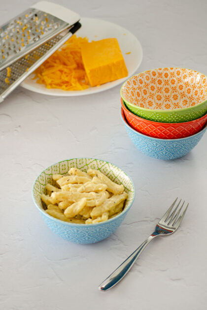 Creamy Four Cheese Pasta in a bowl with shredded cheese in the background