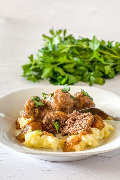 meatballs and gravy served over mashed potatoes with meatball cut open