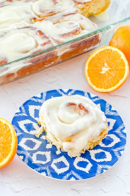 Orange roll on a blue plate and orange halves
