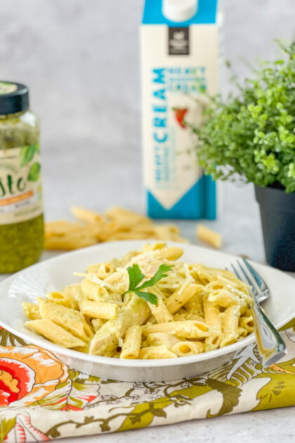 Penne with chicken and pesto with cream and pesto in the background