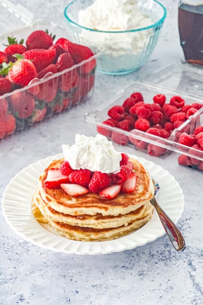 Amish buttermilk pancakes topped with strawberries, raspberries, and whipped cream