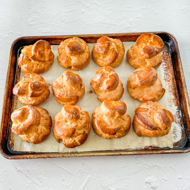 cooked cream puffs on a parchment lined baking sheet