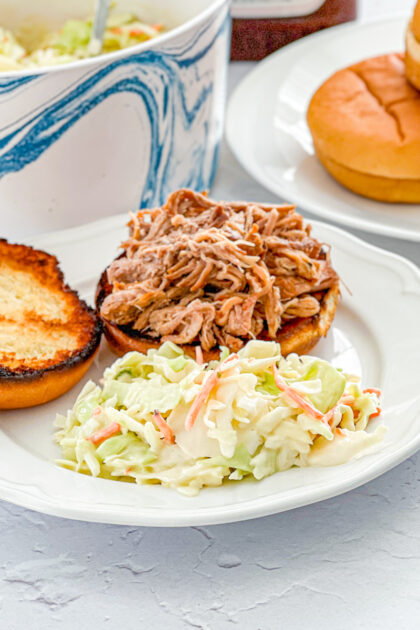 Shockingly Simple Coleslaw on a plate with Slow Cooked Dr. Pepper Pulled Pork Sandwich