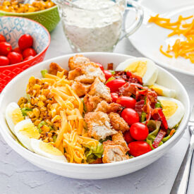 coob salad topped with crispy chicken, cheese, roasted corn, tomato, bacon, and hard boiled egg