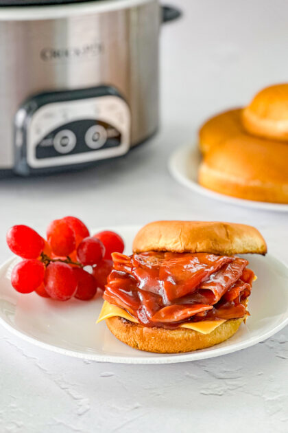 bbq ham sandwich on a plate by a slow cooker