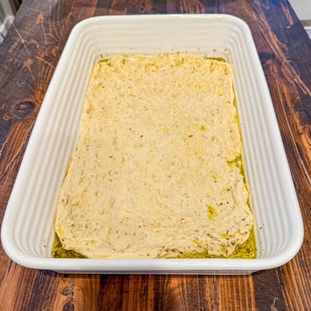 uncooked focaccia dough spread in pan for pizza