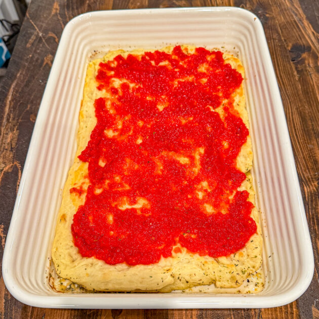 partial baked focaccia pizza crust topped with pizza sauce