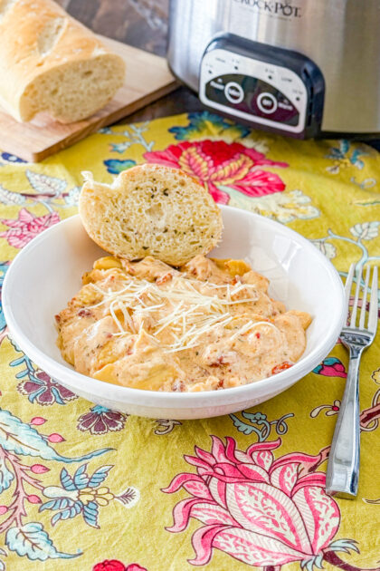 Slow Cooker Marry Me Chicken Tortellini in a white bowl with a piece of garlic bread