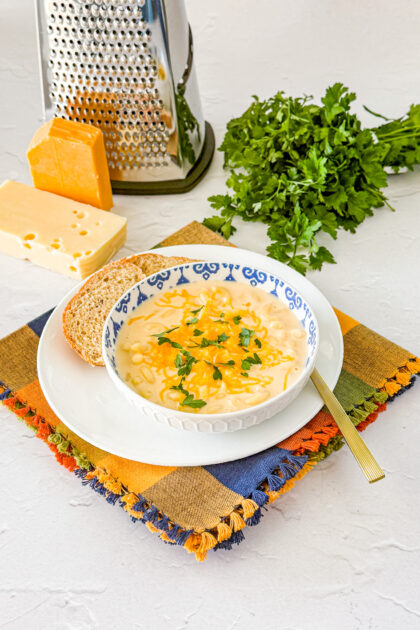 mac and cheese soup in a blue and white bowl with bread on the side