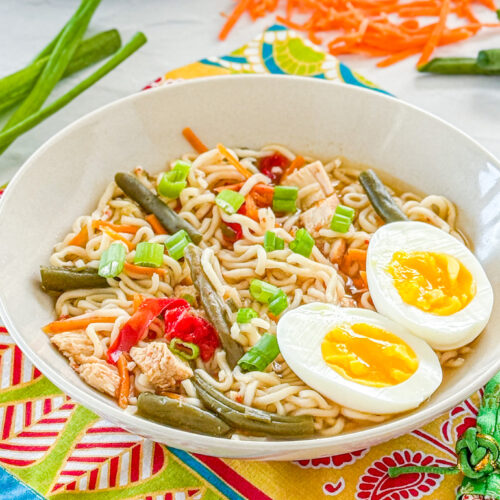 ramen noodles with chicken, carrots, green onion, green beans, red pepper, and soft boiled egg