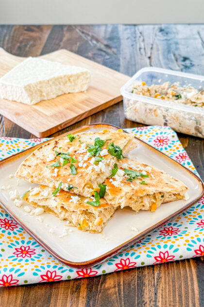 street corn quesadilla wedges in a cream plate sprinkled with cotija cheese and cilantro