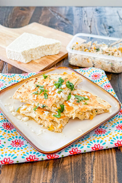 chicken and corn quesadilla wedges with the filling mixture and cotija cheese in the background