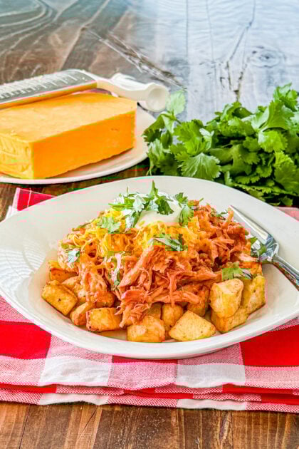Loaded BBQ pork and potato bowl topped with shredded cheese sour cream and cilantro