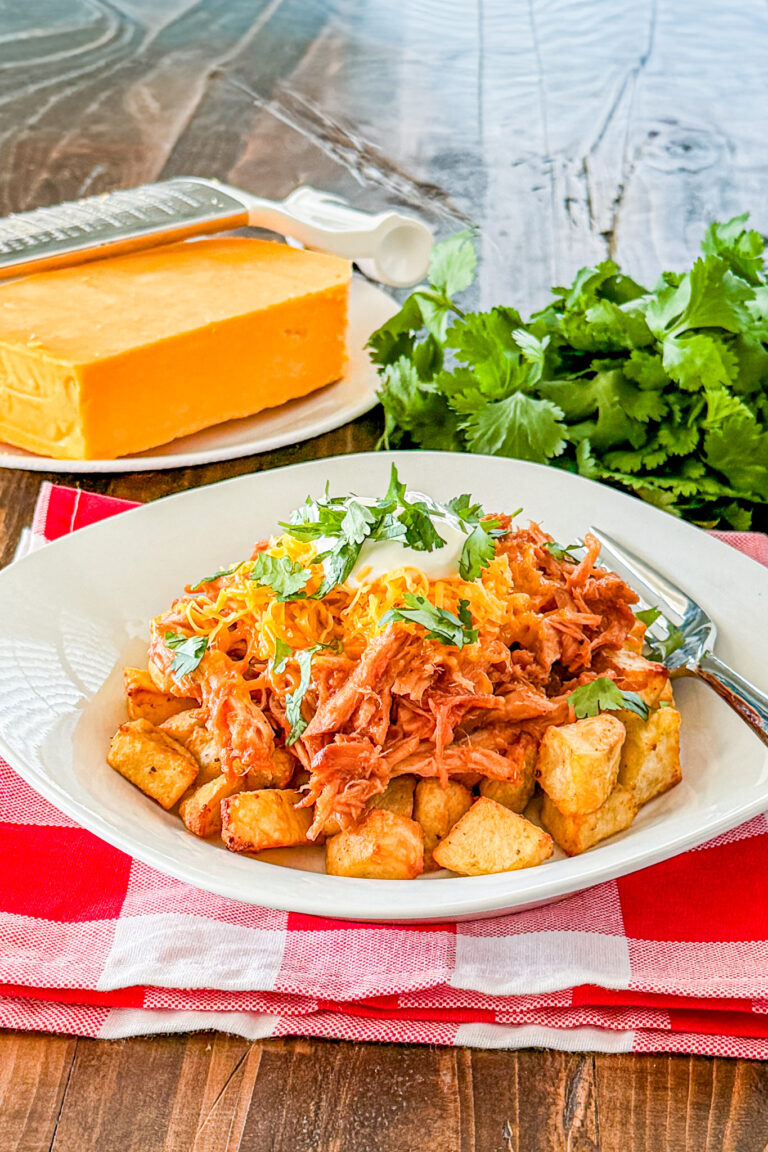 Loaded BBQ pork and potato bowl topped with shredded cheese sour cream and cilantro