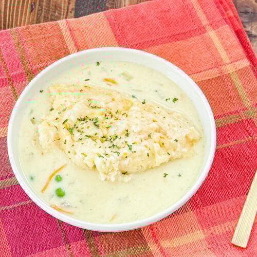 Close-up of fluffy cheddar biscuit dumplings cooked in slow cooker chicken and gravy.