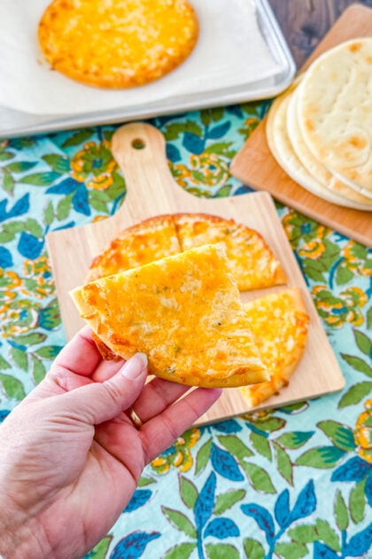 Overhead view of cheesy garlic pita bread cut into wedges.
