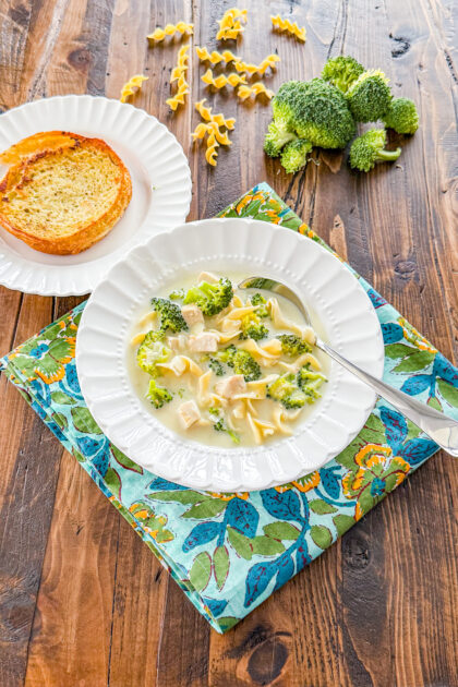 bowl of alfredo soup with egg needles, chunks of chicken, and broccoli florets