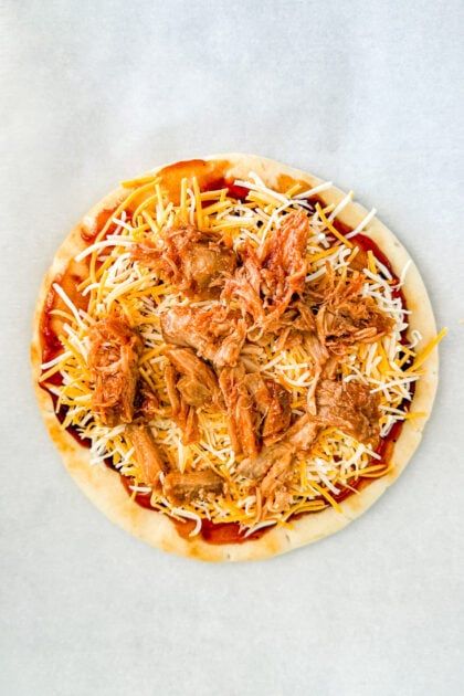 BBQ sauce, shredded cheese, and pulled pork layered on pita bread before baking.