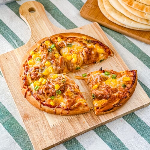 BBQ pulled pork pita pizza garnished with green onion after baking.