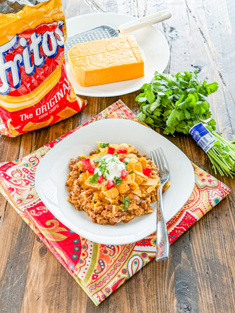Instant Pot Frito Pie topped with shredded cheese and crunchy Fritos in a serving bowl.