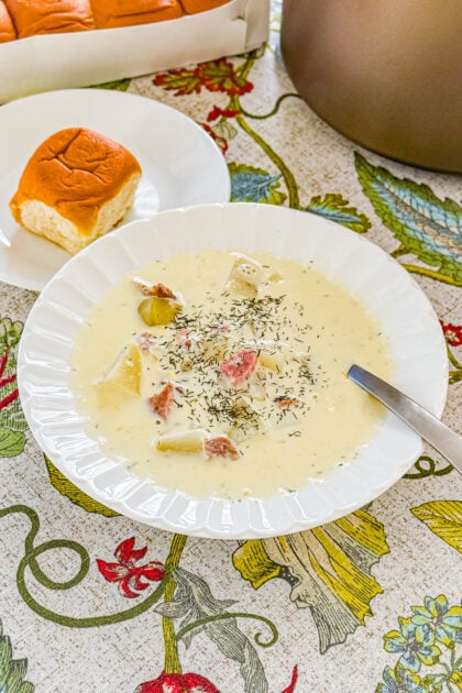 Creamy ham and potato soup with dill served with roll on the side