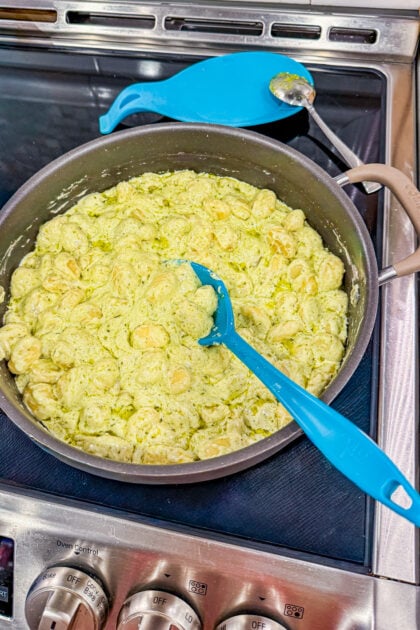 Creamy pesto gnocchi in a skillet with Parmesan cheese