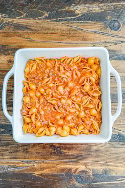 Overhead view of cheesy cheeseburger pasta bake in a baking dish before cheese topping