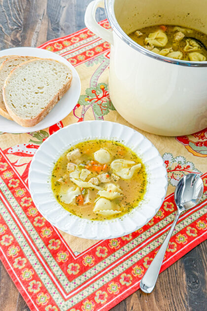 Top view of chicken tortellini soup with carrots, celery, and herbs
