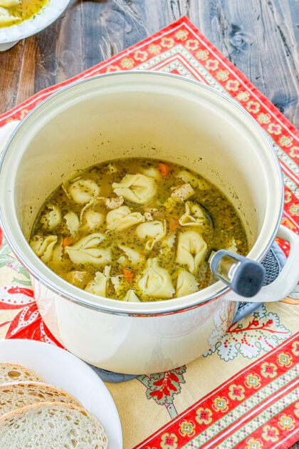 Chicken and tortellini added to soup with Italian seasoning and vegetables in a pot