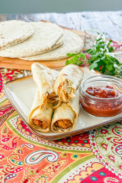 Close-up of crispy baked chicken taquitos with creamy filling broken in half
