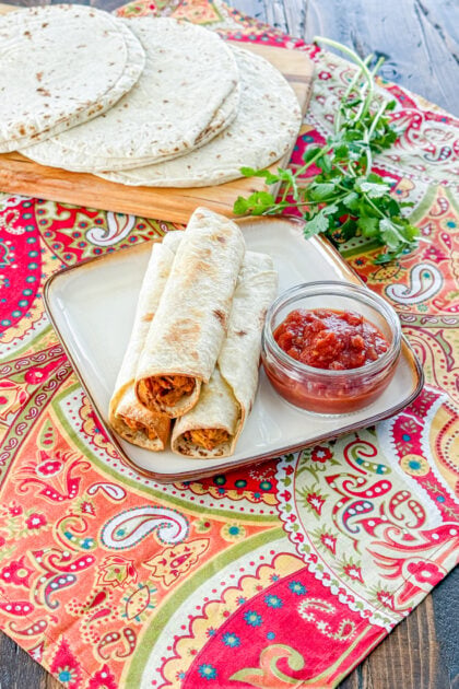 Serving of baked chicken taquitos on a plate with salsa