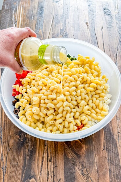 Italian pasta salad with pasta being added along with dressing in a large bowl