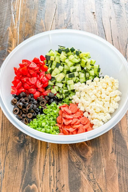 Ingredients for easy Italian pasta salad including mozzarella, cucumbers, tomatoes, olives, green onion, and pepperoni