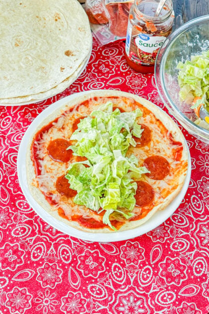 Pizza tortilla topped with Caesar salad before being rolled into a wrap